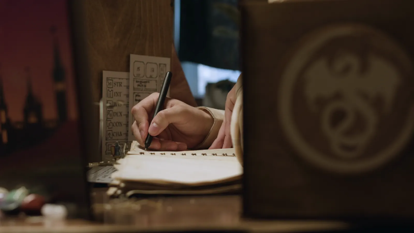 Hands writing in a notebook by lamplight.