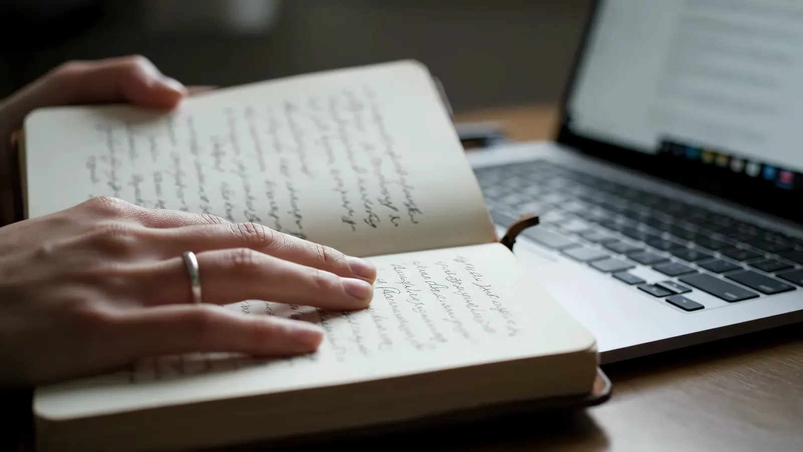 A notebook and laptop on a working desk.