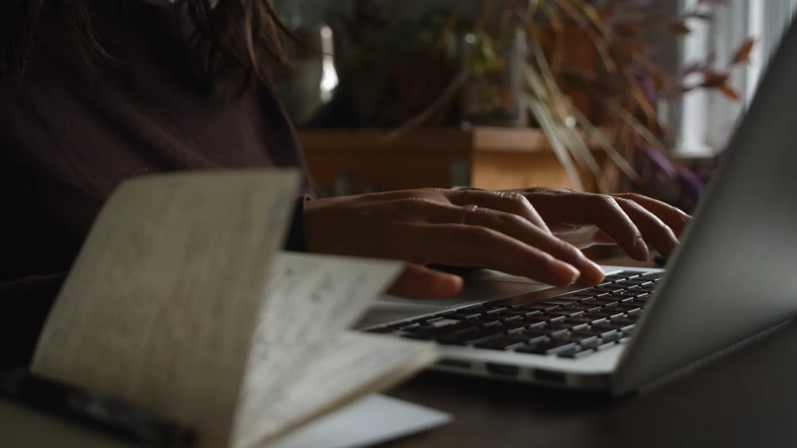 A working desk in low light, notes beside a screen.